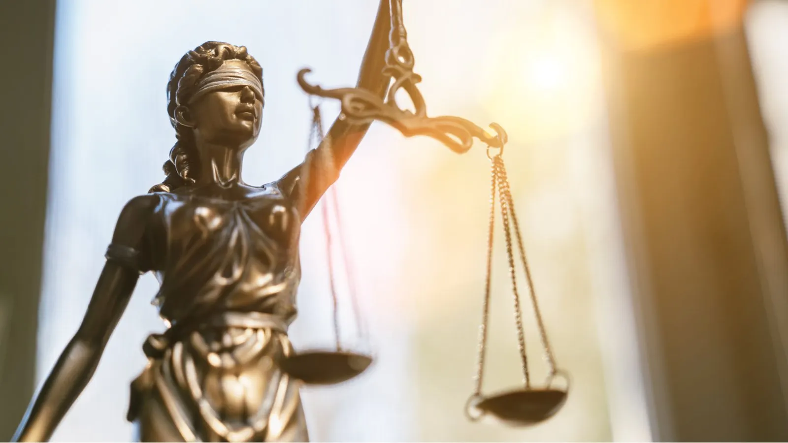 Lady Justice statue with light shining behind. Image: Shutterstock